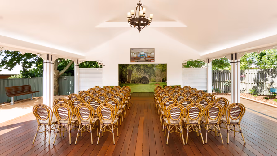 Outdoor chapel with rows of wicker chairs.