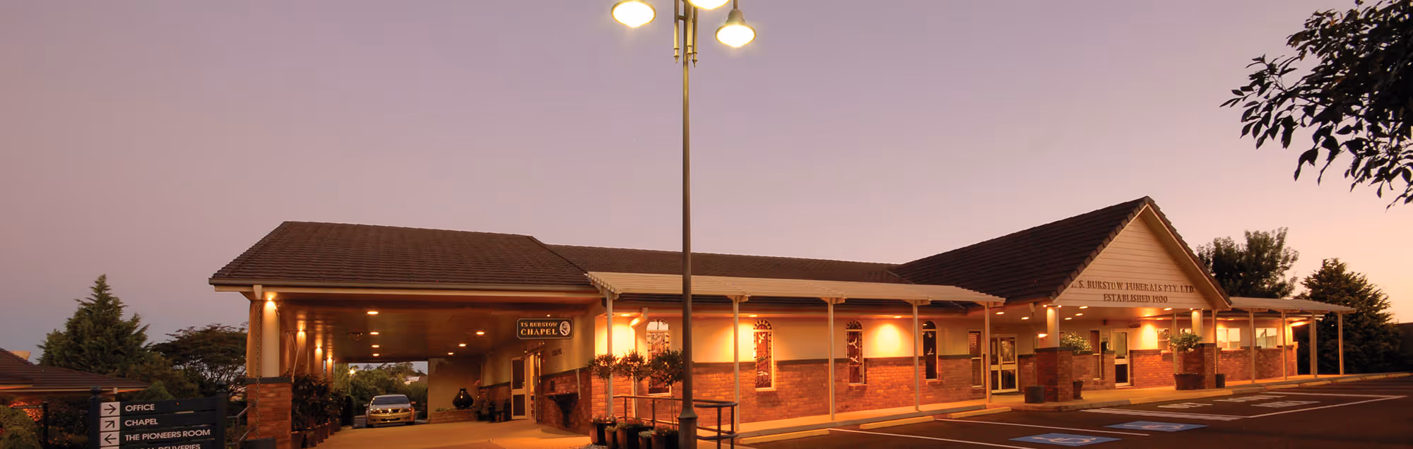 The TS Burstow Funeral Home at dusk with soft lighting.