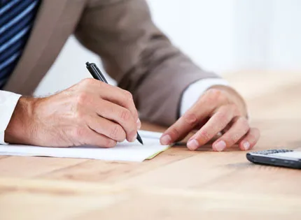 A person's hands writing on a piece of paper.