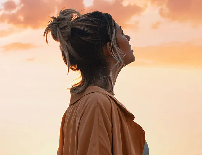 A person looking up at a sunset, lost in thought.