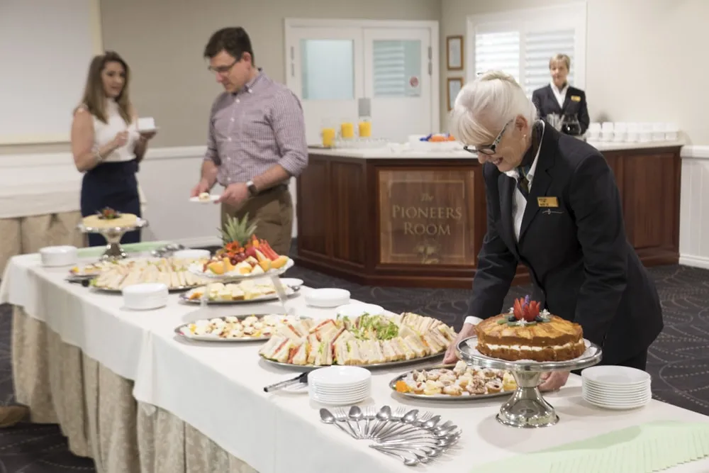 Guests mingling around a buffet table with food.