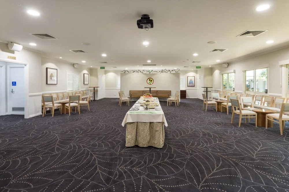 Large room with tables arranged for a formal gathering.
