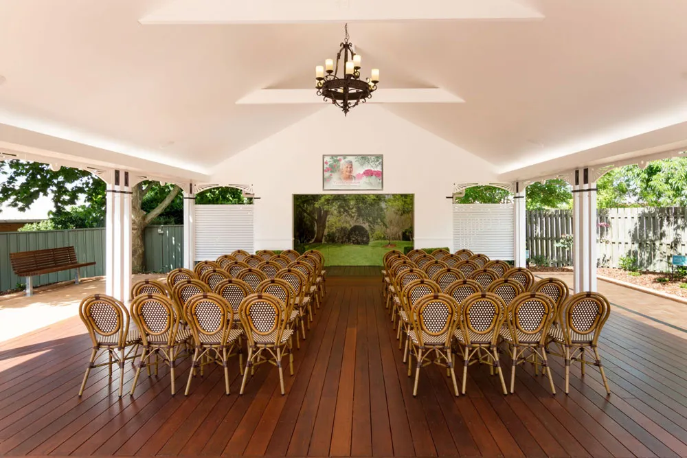 Outdoor covered area with rows of chairs and a screen.