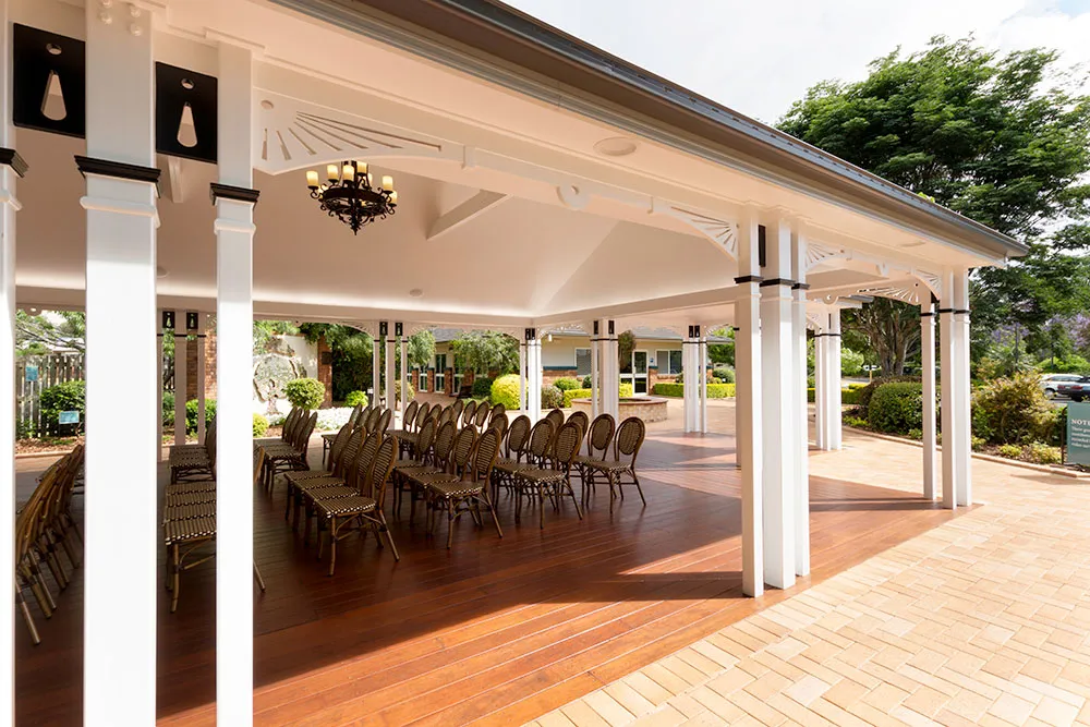 Outdoor gazebo with rows of chairs and a chandelier.