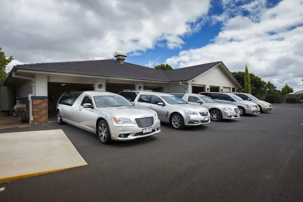 Line of white modern hearses parked outside.